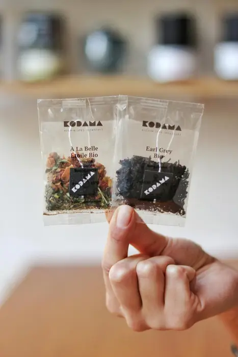 Deux sachets individuels de thé Kodama tenus à la main, À la Belle Étoile bio et Earl Grey bio